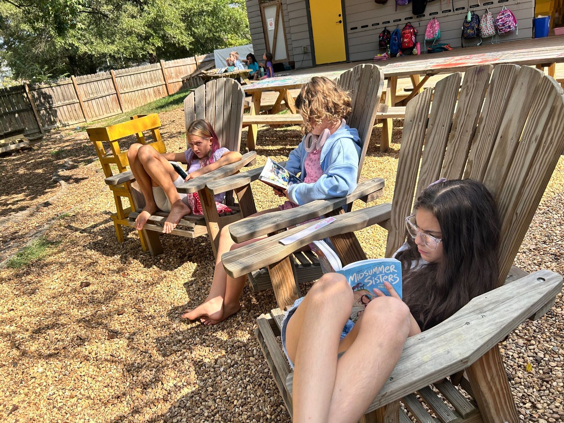 Kids reading in Adirondack chairs outdoors