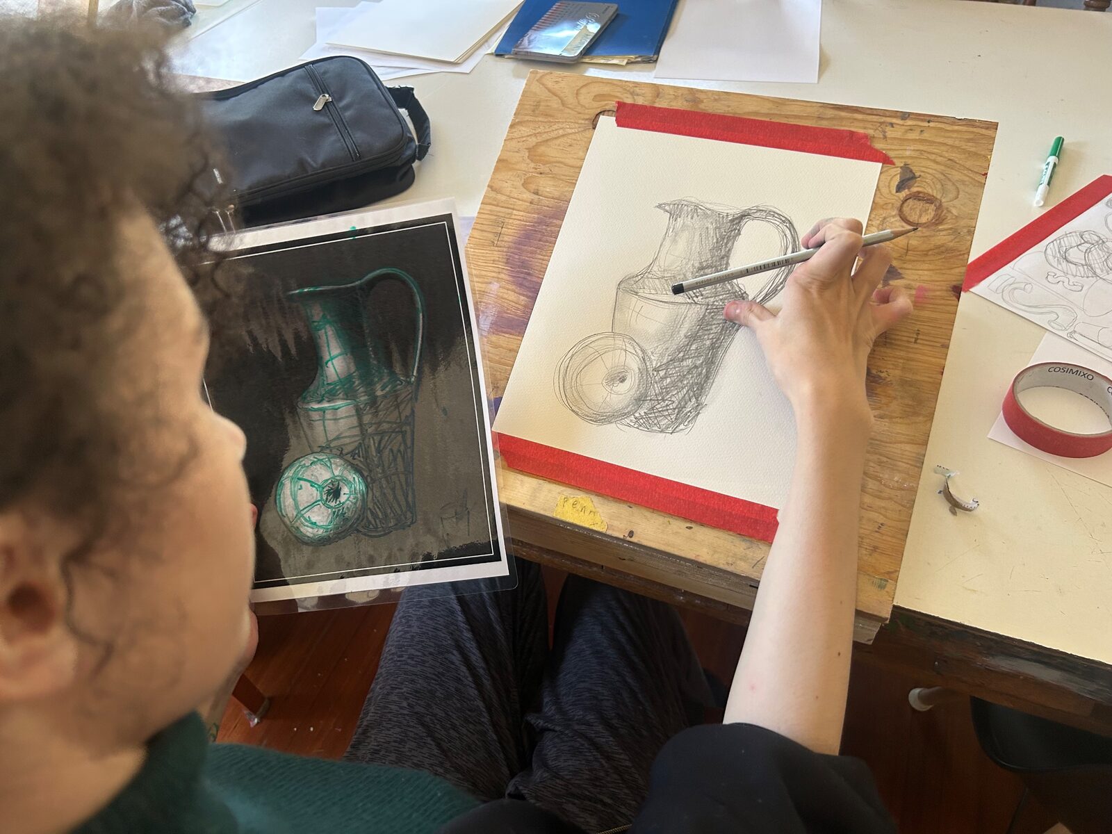 A kid drawing in pencil at a table in the art room