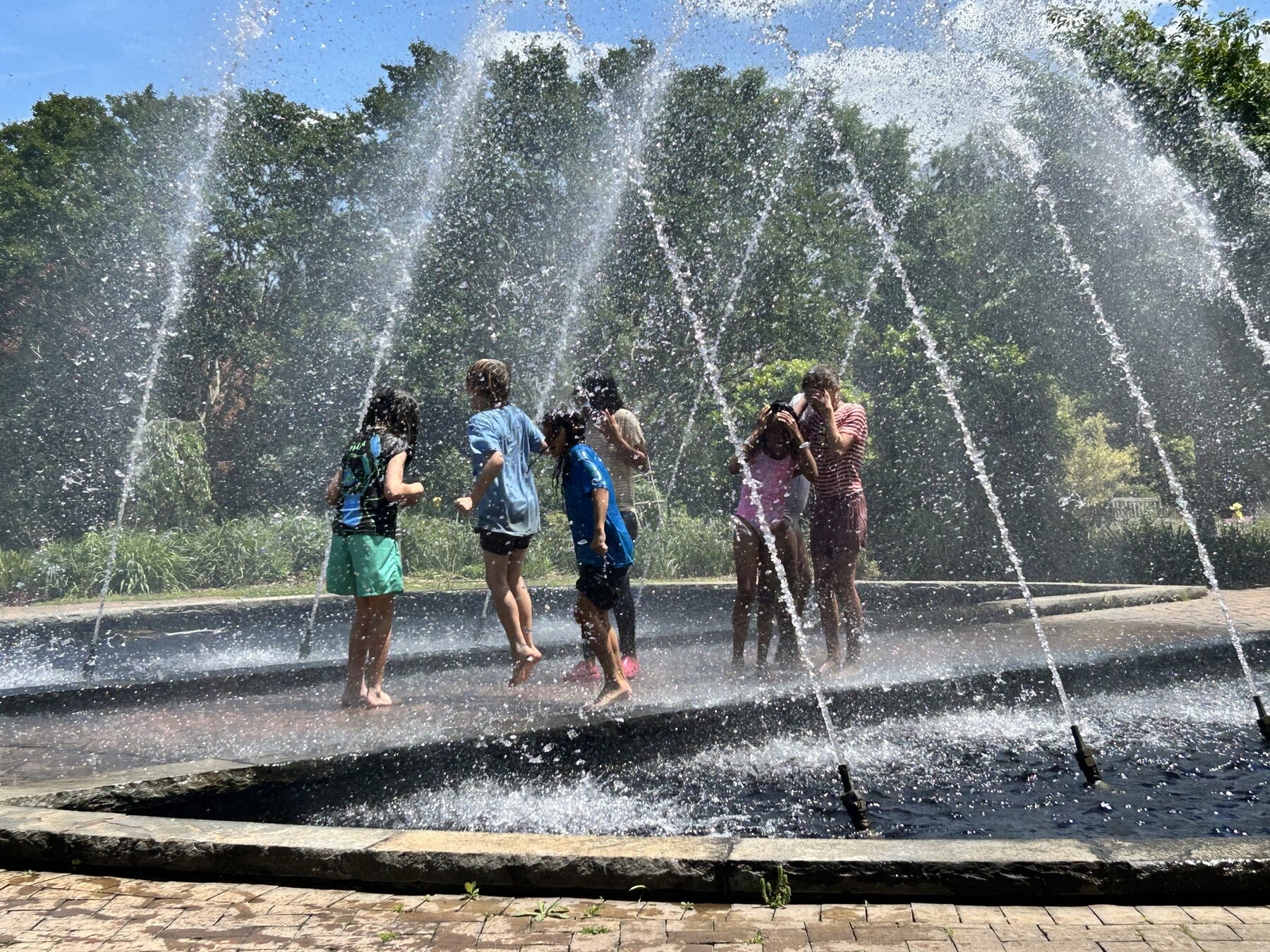 Kids running through a splash fountain on a hot day